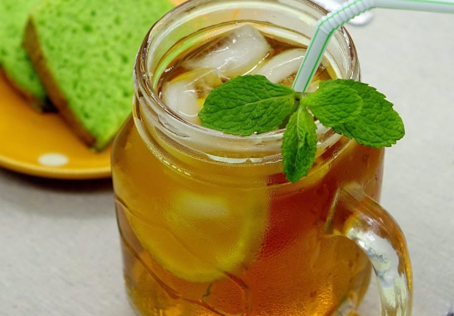 Lemon Iced Tea in a glass container and green cake in the background