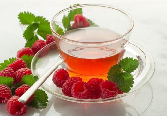 raspberry loose leaf tea in a glass with raspberries on the edge