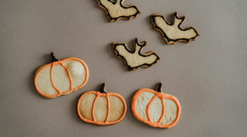 Pumpkin and bat-shaped halloween cookies for a halloween tea party.