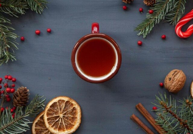 Festive cup of tea surrounded by candy cane and Christmas decorations.