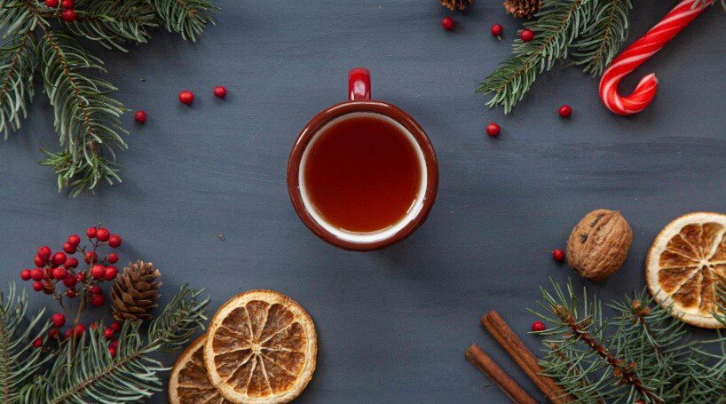 Festive cup of tea surrounded by candy cane and Christmas decorations.