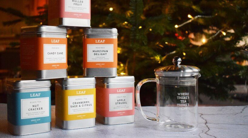 A stack of festive Leaf Christmas tea tins, alongside a Leaf tea pot. 