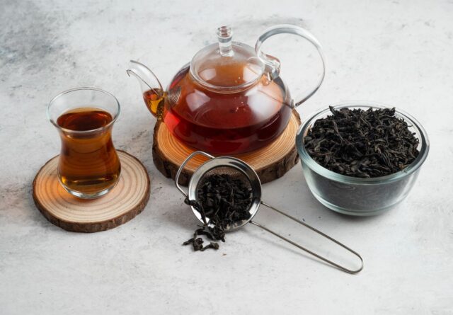 Pu-erh tea served in a glass teapot and cup with loose tea leaves, showcasing its rich colour and properties